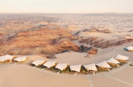 Six Senses Southern Dunes, Blick von oben auf zeltähnliche Villen inmitten einer felsigen Wüstenlandschaft