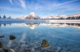 Ein See in Tirol mit den Alpen im Hintergrund.
