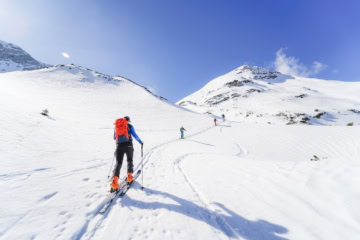 Langläufer in den Bergen mit blauem Himmel