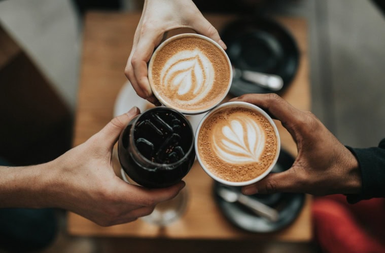 drei Menschen halten Kaffee