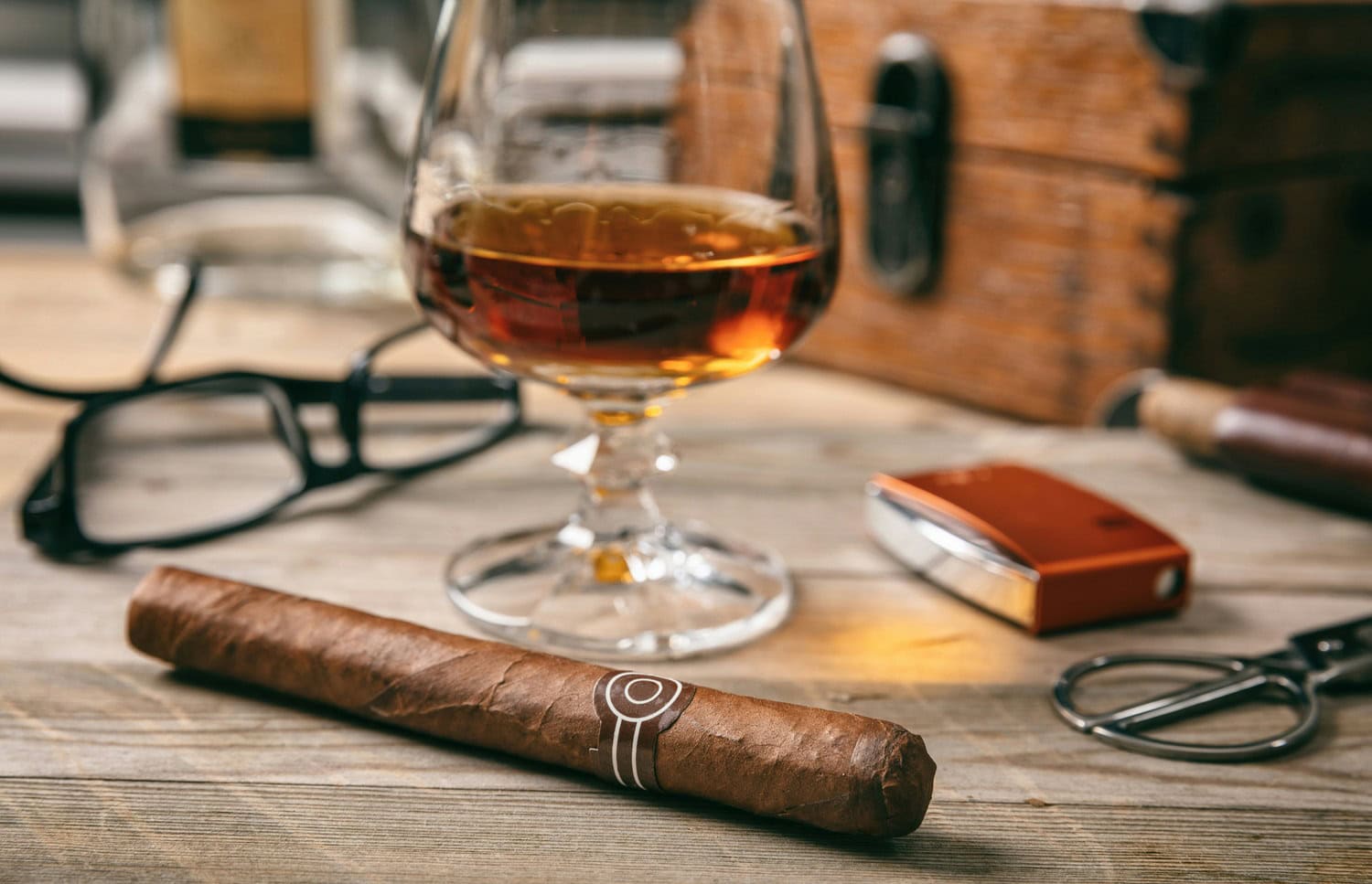 Zigarre mit Cutter und einem Glas Cognac auf einem Holztisch