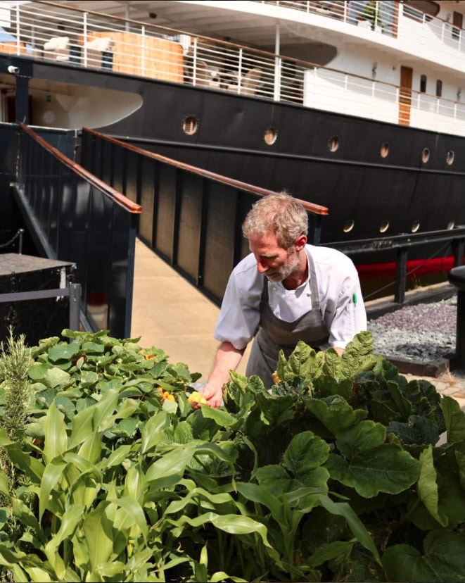 Koch vor dem Schiff, der gerade Salat prüft.