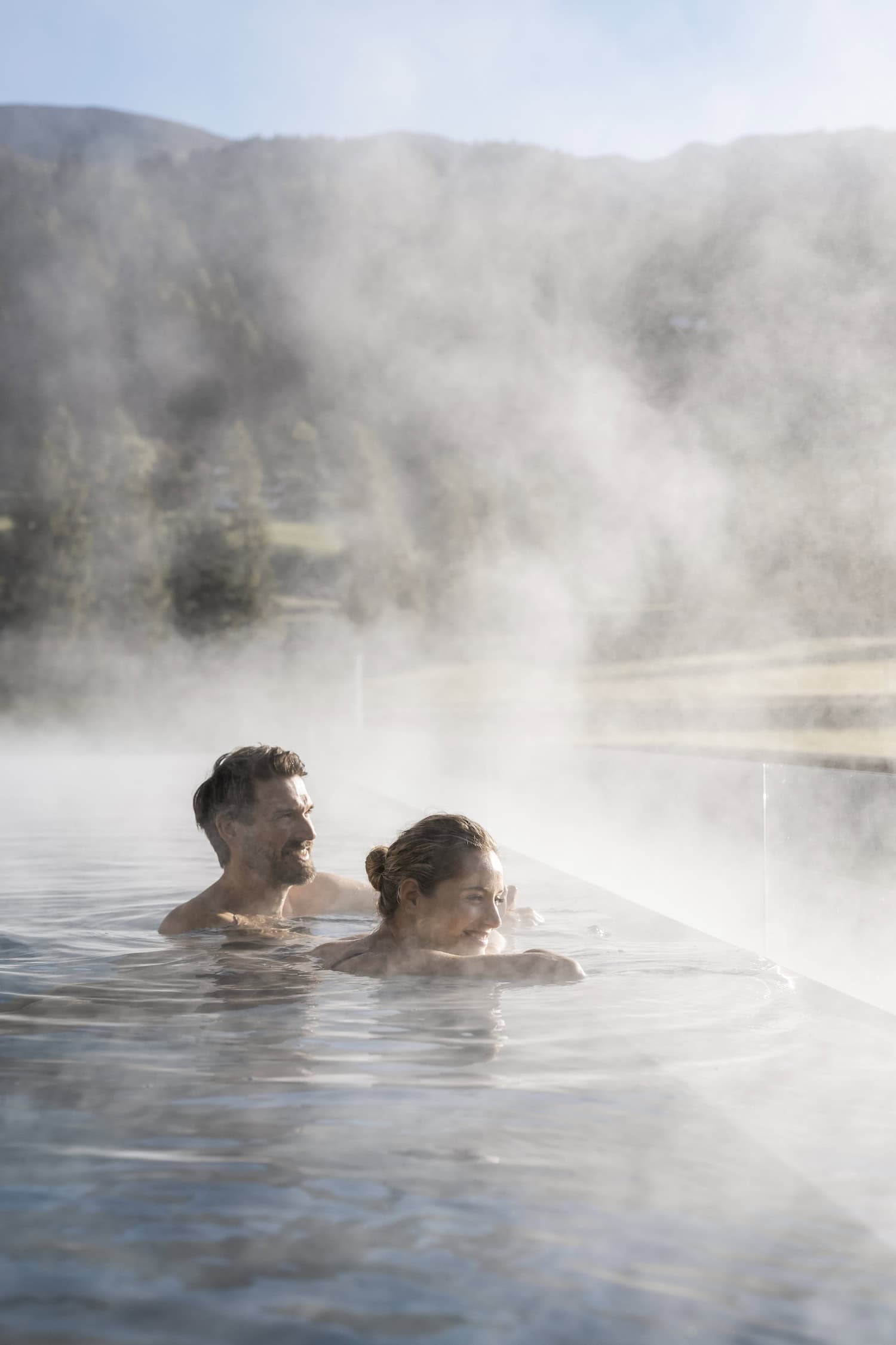 Paar im dampfenden Infinitypool in den Bergen im Hotel Monika