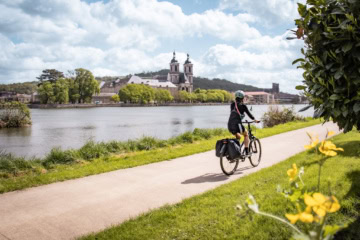 Eine Frau radelt auf einem Fernradweg in Frankreich.