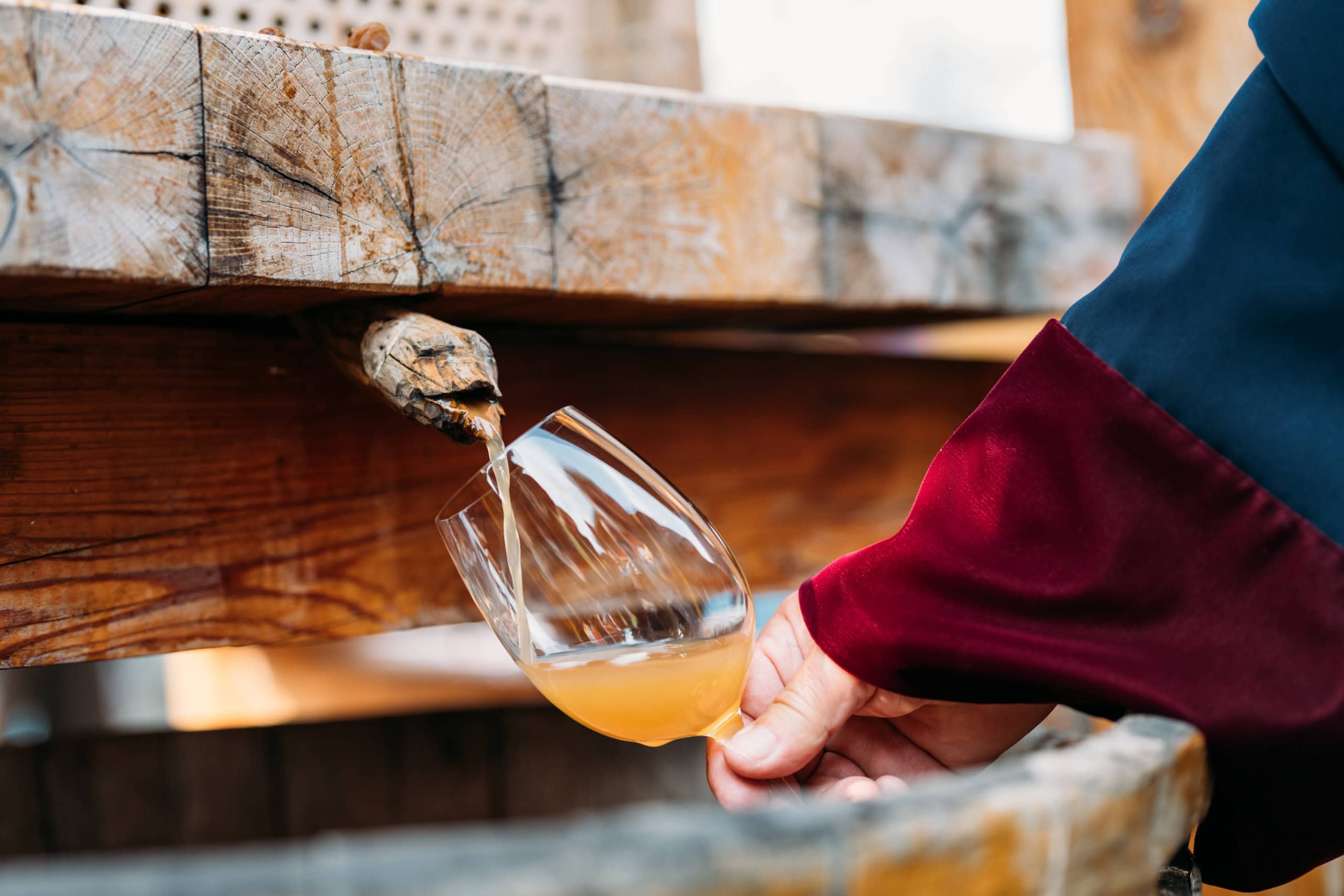 Wein fließt aus einem Fass in ein Glas. 