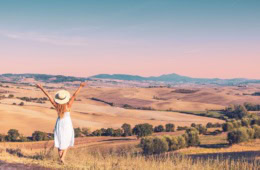 Frau in weißem Kleid erfreut sich an der Landschaft der Toskana