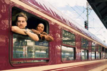 Junges Paar blickt aus Nachtzug in Prag im Bahnhof aus dem Fenster