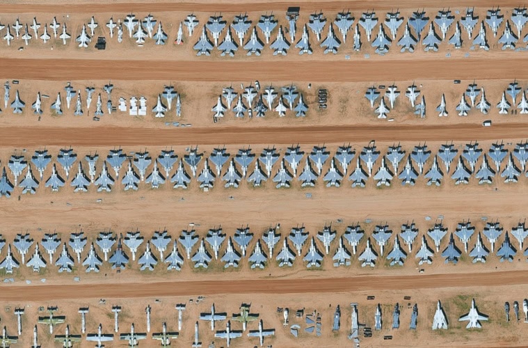 Drohnenansicht des Flugzeugfriedhofs »Boneyard« in Arizona. In der Wüste stehen zahllose ausrangierte Militärflugzeuge nebeneinander.