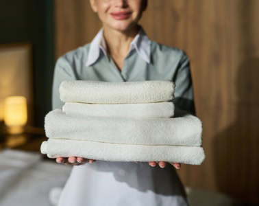 Frau reicht Handtücher im Hotel