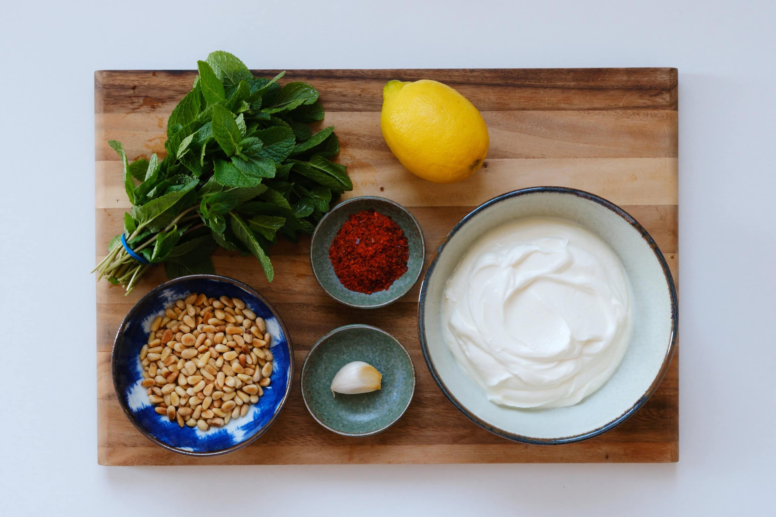 Rezept für Orecchiette mit Joghurt: Die Zutaten für die Sauce liegen auf einem Holzbrett (Bild).