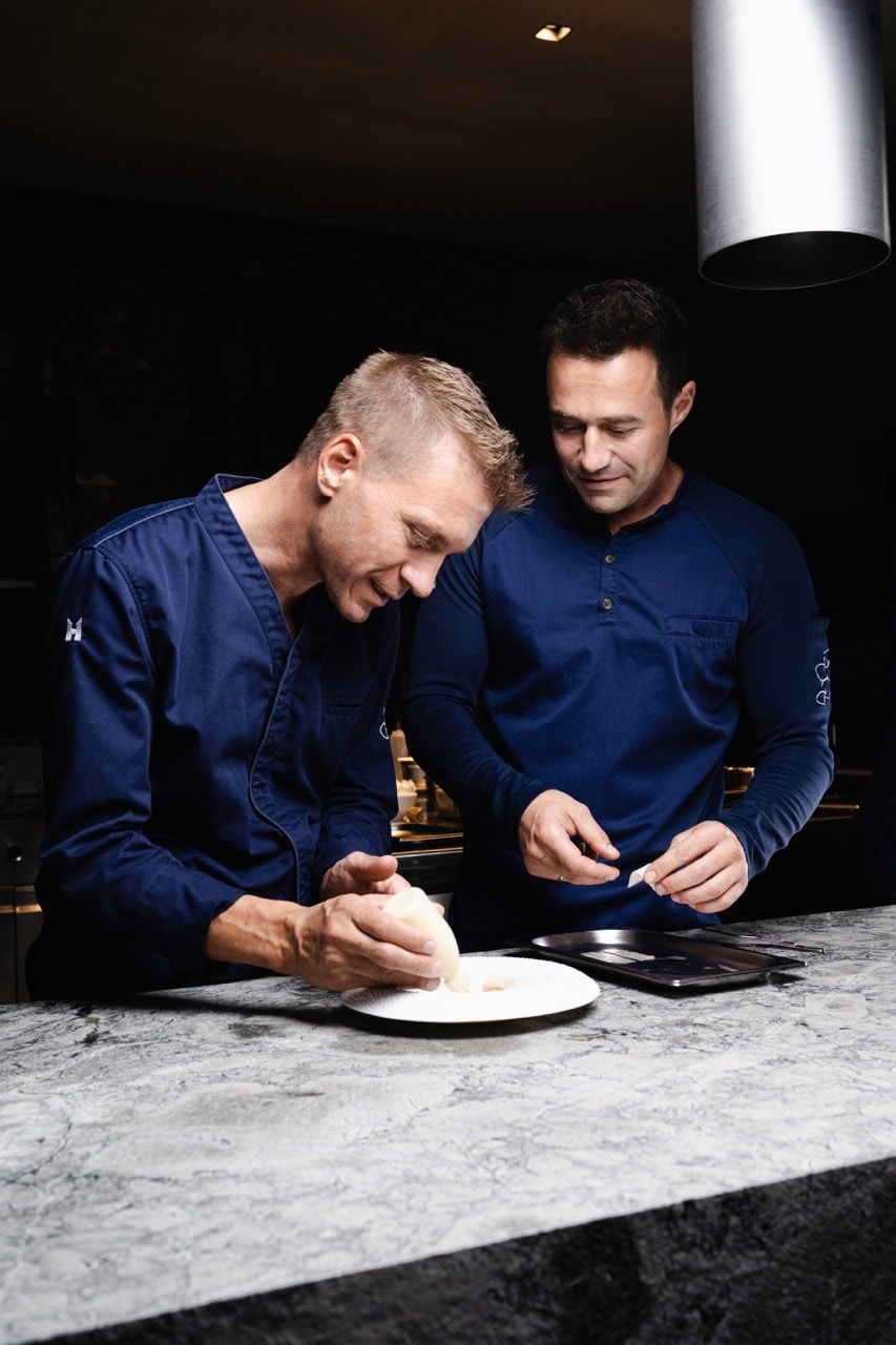 Andreas Senn und Christian Geisler beim gemeinsamen Anrichten eines Gerichts an einer Marmortheke