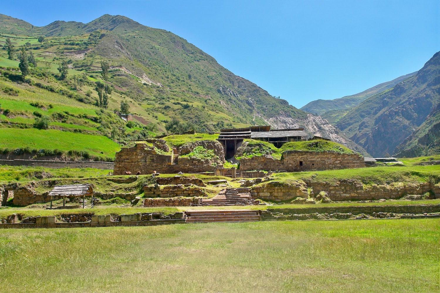 Blick auf die Ruinen von Chavin-de-Huantar, im Hintergrund mit hohen Bergen und blauem Himmel.
