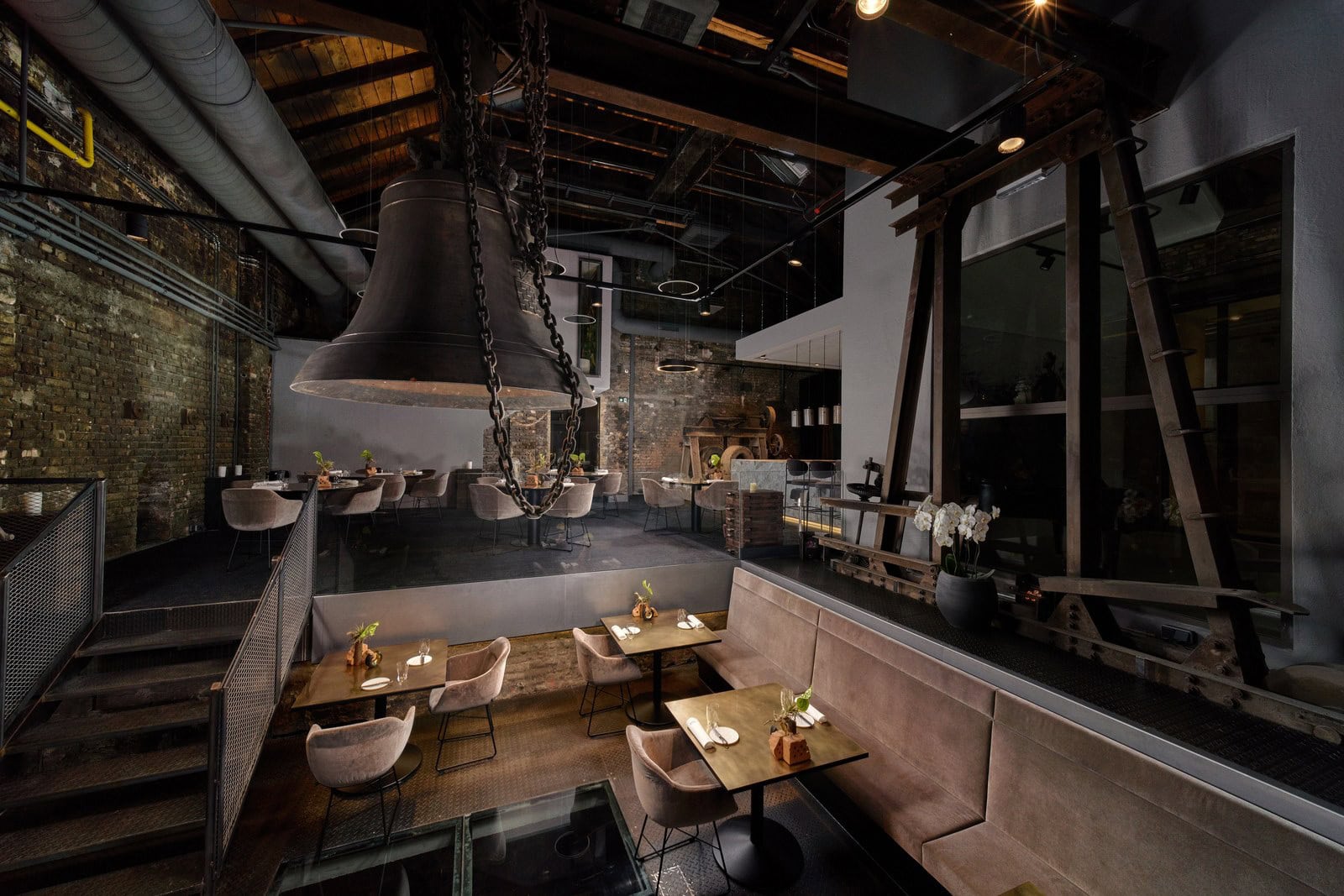 Industrieller Gastraum des Senns Restaurant im Gusswerk mit großer Glocke, Backsteinwänden und Loungebereich