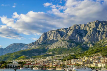 Blick vom Meer auf die Stadt Makarska in Dalmatien in Kroatien, im Hintergrund die Berge.