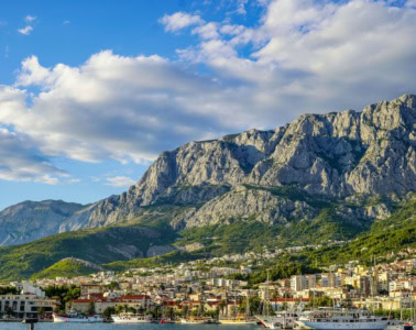 Blick vom Meer auf die Stadt Makarska in Dalmatien in Kroatien, im Hintergrund die Berge.