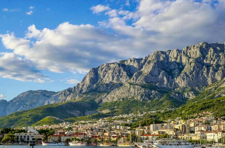 Blick vom Meer auf die Stadt Makarska in Dalmatien in Kroatien, im Hintergrund die Berge.