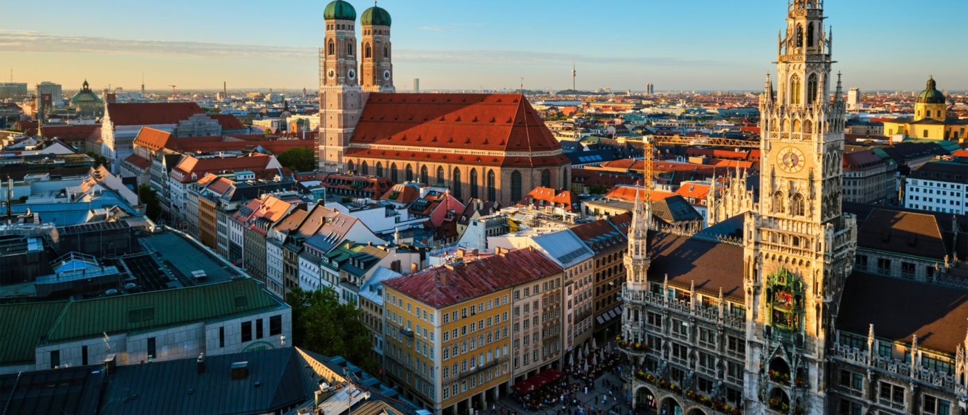 Panoramaaufnahme Münchens mit dem Marienplatz und der Frauenkirche im Licht der aufgehenden Sonne