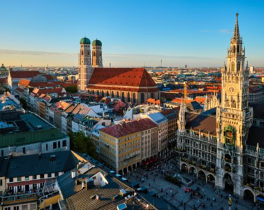 Panoramaaufnahme Münchens mit dem Marienplatz und der Frauenkirche im Licht der aufgehenden Sonne
