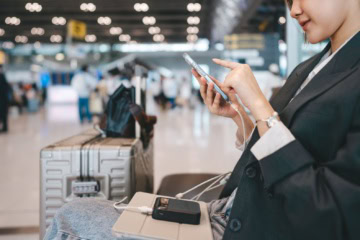 Reisende mit Smartphone und Powerbank am Flughafen