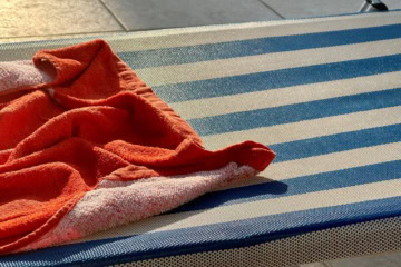 Reservierte Poolliege: Rotfarbenes Handtuch auf blau-weiß gestreifter Liege platziert