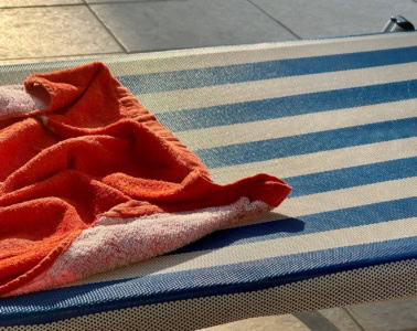 Reservierte Poolliege: Rotfarbenes Handtuch auf blau-weiß gestreifter Liege platziert