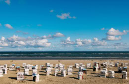 Auf der Ostfriesischen Insel Spiekeroog stehen zahlreiche Strandkörbe am Strand, bereit für den Urlaub.