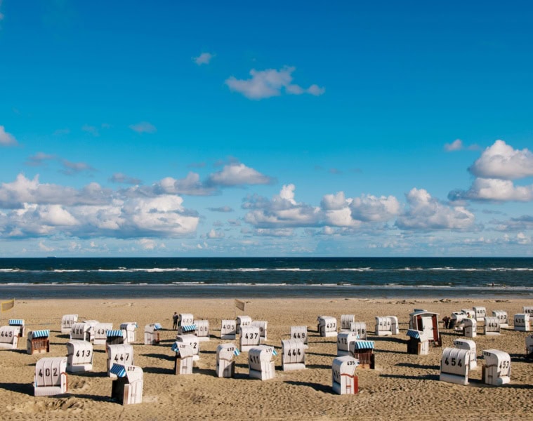 Auf der Ostfriesischen Insel Spiekeroog stehen zahlreiche Strandkörbe am Strand, bereit für den Urlaub.