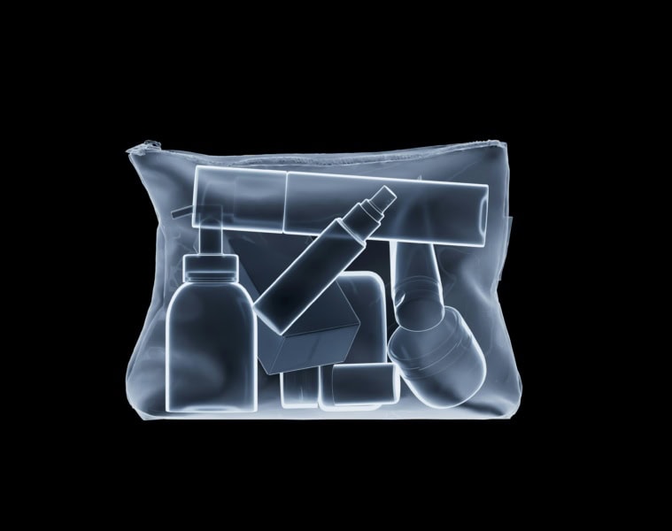 Röntgenaufnahme eines prall gefüllten transparenten Kulturbeutels mit Reise-Kosmetik: Flaschen, Tuben und Tiegel im Handgepäckformat