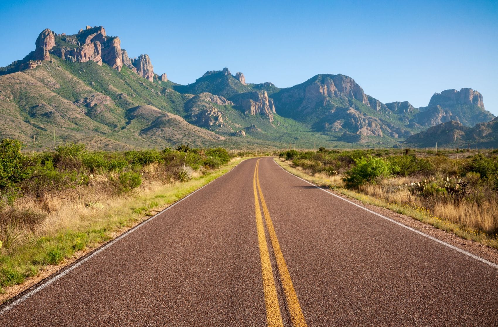 Eine Landstraße verläuft durch die Berg- und Wüstenlandschaft des Big Bend National Park in Texas.