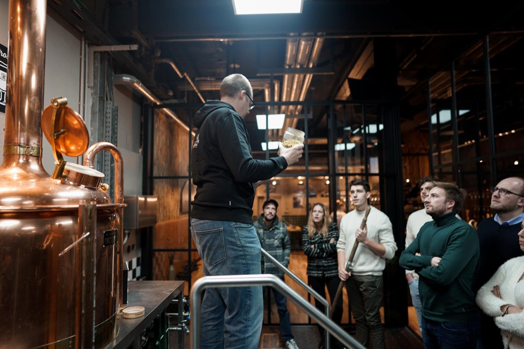Besucher verfolgen eine Führung durch die Brauerei Brasserie Nationale in Luxemburg, während ein Mitarbeiter die Brauprozesse an einer kupfernen Sudanlage erklärt.