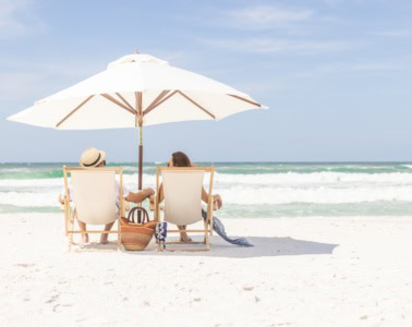 Händchenhaltendes Pärchen unter einem Sonnenschirm auf Liegestühlen am Strand von Florida