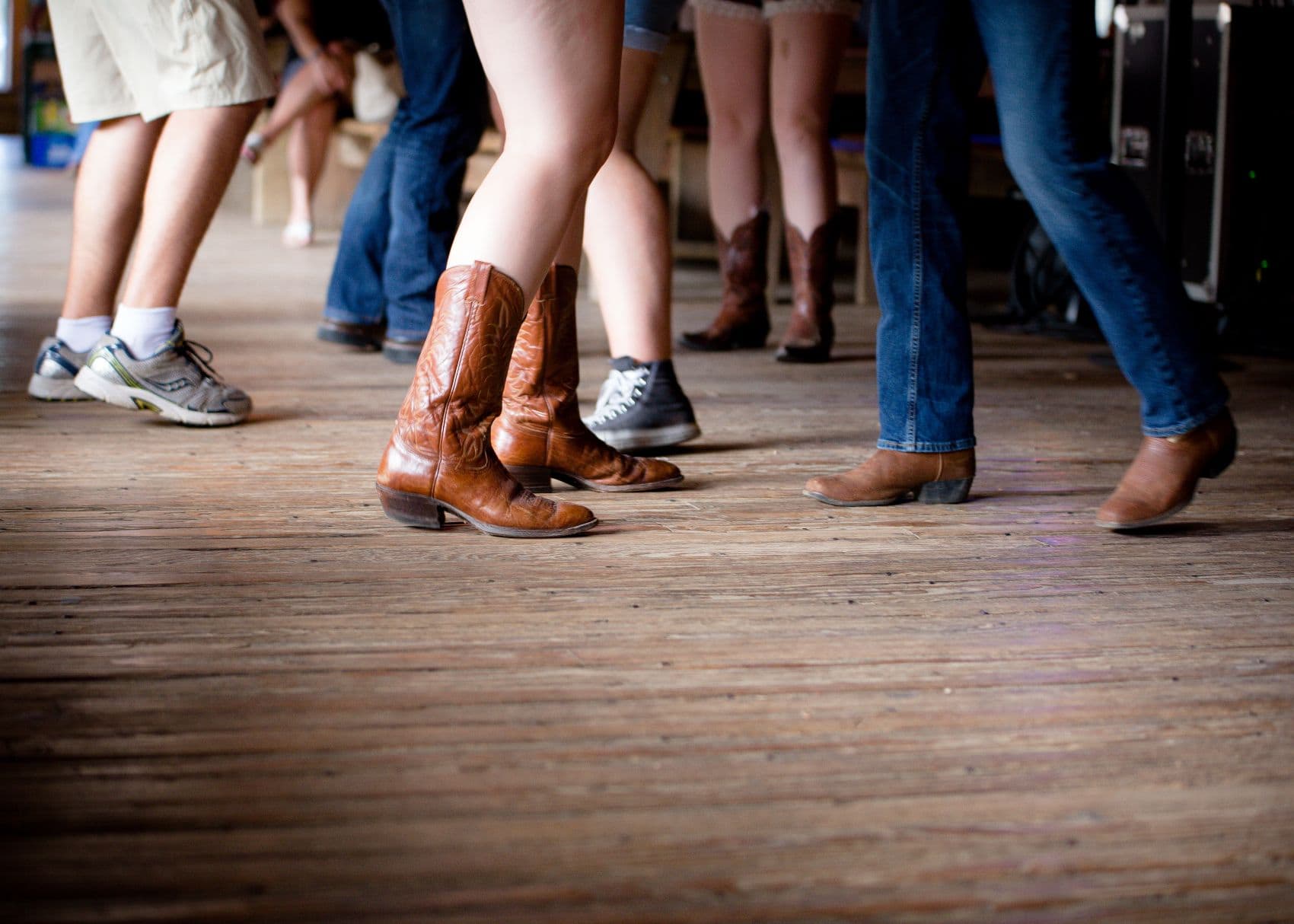 Cowboyboots und andere Schuhe auf einer Tanzfläche in der legendären Gruene Hall in Texas während eines Country-Tanzabends.
