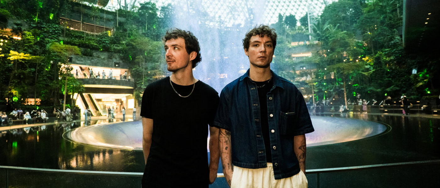 Heiko und Roman Lochmann stehen vor dem Wasserfall und der begrünten Glaskuppel im Jewel Changi Airport in Singapur.