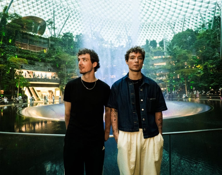 Heiko und Roman Lochmann stehen vor dem Wasserfall und der begrünten Glaskuppel im Jewel Changi Airport in Singapur.