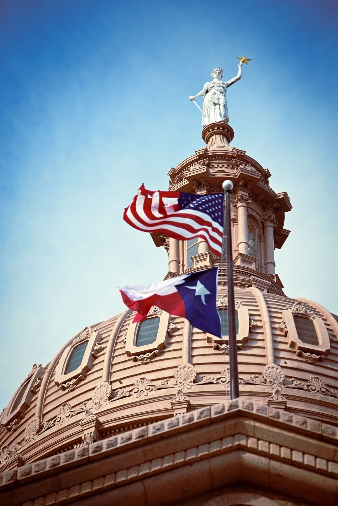 Kuppel des Texas State Capitol in Austin mit der Flagge von Texas und der US-Flagge im Vordergrund.