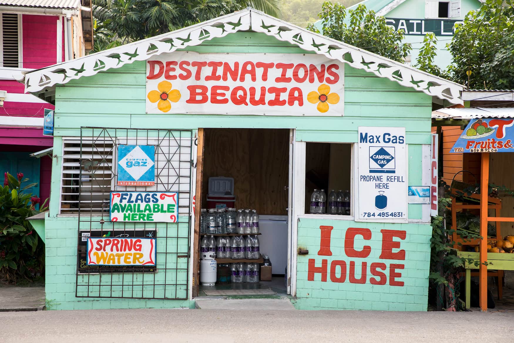 Buntes Holzhaus mit dem Schriftzug »Destinations Bequia« am Hafen von Port Elizabeth, Bequia, Grenadinen