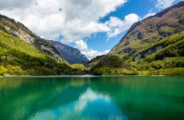 Türkisgrüner Bergsee im Trentino, umgeben von Bergen und Wäldern