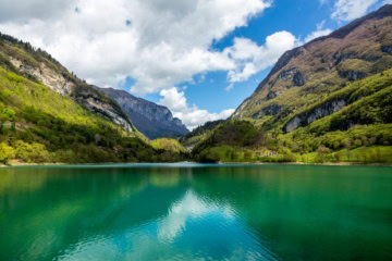 Türkisgrüner Bergsee im Trentino, umgeben von Bergen und Wäldern
