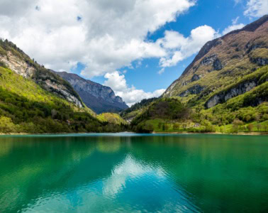 Türkisgrüner Bergsee im Trentino, umgeben von Bergen und Wäldern