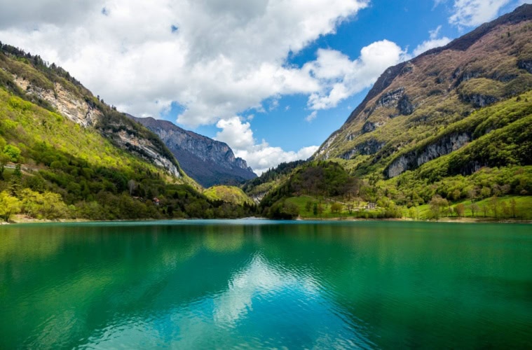 Türkisgrüner Bergsee im Trentino, umgeben von Bergen und Wäldern