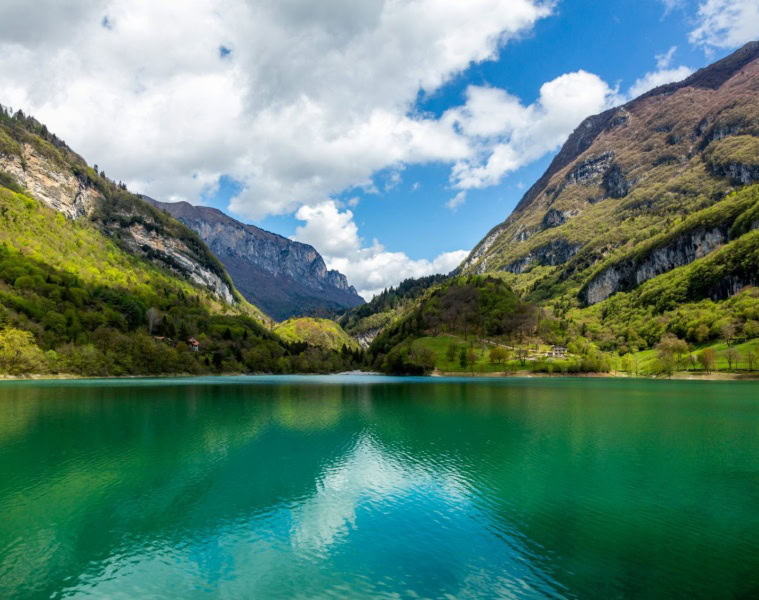 Türkisgrüner Bergsee im Trentino, umgeben von Bergen und Wäldern