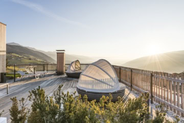 Die Terrasse im Hotel Ambet in Südtirol. Auf der Terrasse stehen zwei runde Liegen mit Sonnenschutz