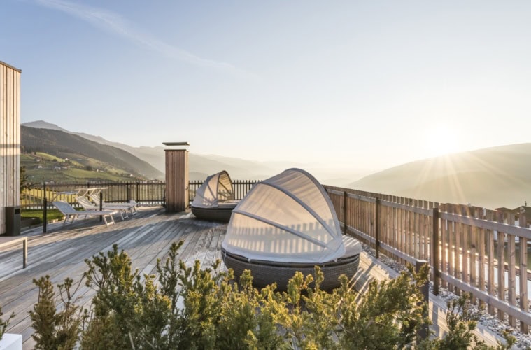 Die Terrasse im Hotel Ambet in Südtirol. Auf der Terrasse stehen zwei runde Liegen mit Sonnenschutz