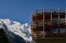 Detailansicht der gebogenen Holzlatten-Fassade des Matteo-Thun-Anbaus am Hotel Bella Vista vor dem verschneiten Ortlermassiv.