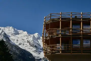 Detailansicht der gebogenen Holzlatten-Fassade des Matteo-Thun-Anbaus am Hotel Bella Vista vor dem verschneiten Ortlermassiv.