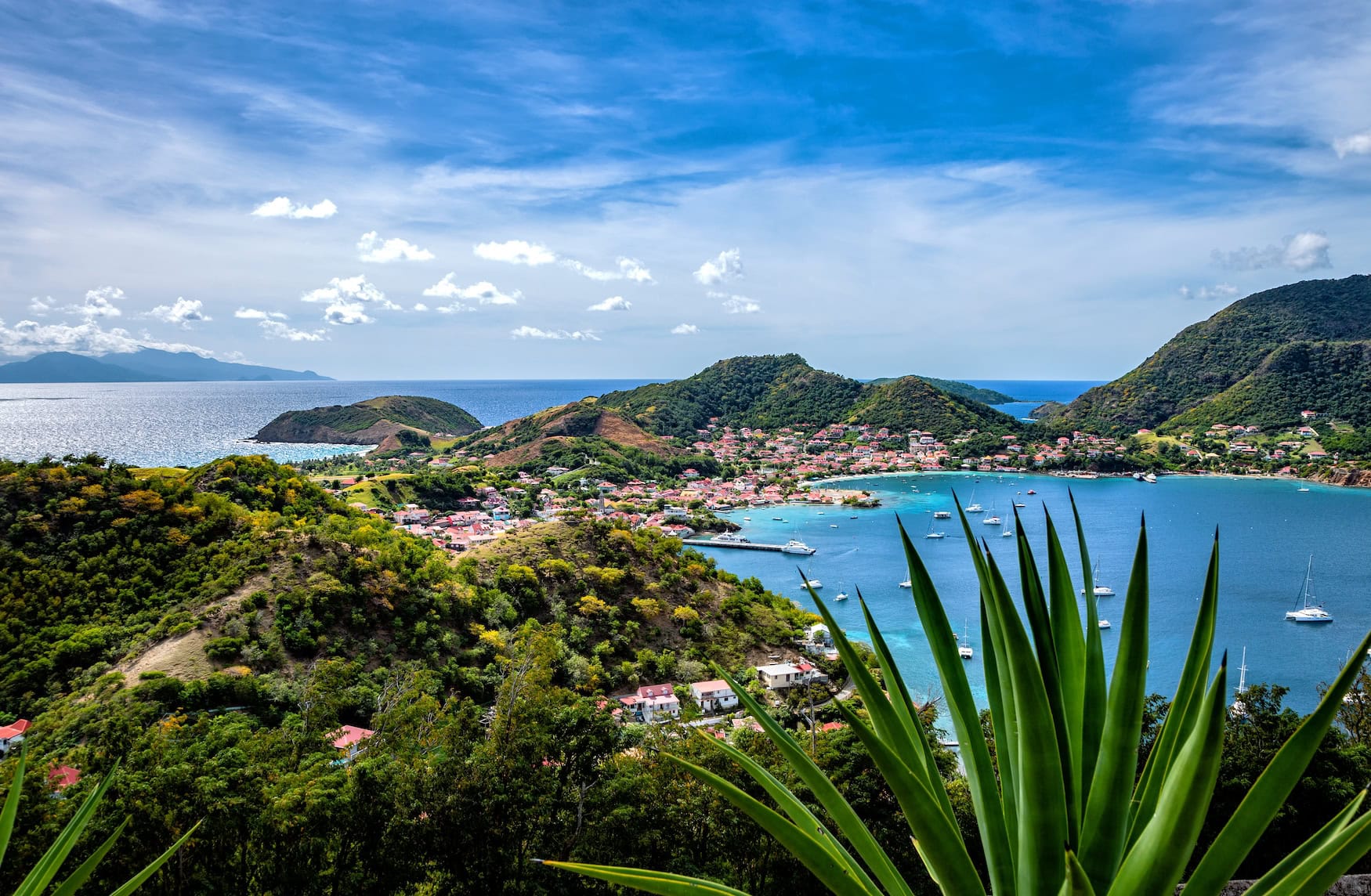 Panoramablick über Terre-de-Haut, Îles des Saintes, mit roten Ziegeldächern, grünen Hügeln und Segelbooten in der türkisblauen Bucht