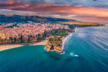 Die Stadt Tropea in Kalabrien mit der Drohne aufgenommen, im Licht der untergehenden Sonne. Am Horizont kündigt sich ein Regenschauer an.