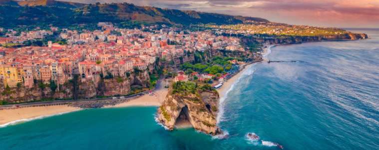 Die Stadt Tropea in Kalabrien mit der Drohne aufgenommen, im Licht der untergehenden Sonne. Am Horizont kündigt sich ein Regenschauer an.