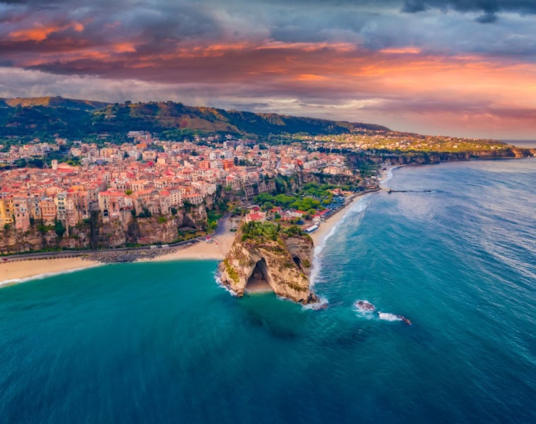 Die Stadt Tropea in Kalabrien mit der Drohne aufgenommen, im Licht der untergehenden Sonne. Am Horizont kündigt sich ein Regenschauer an.