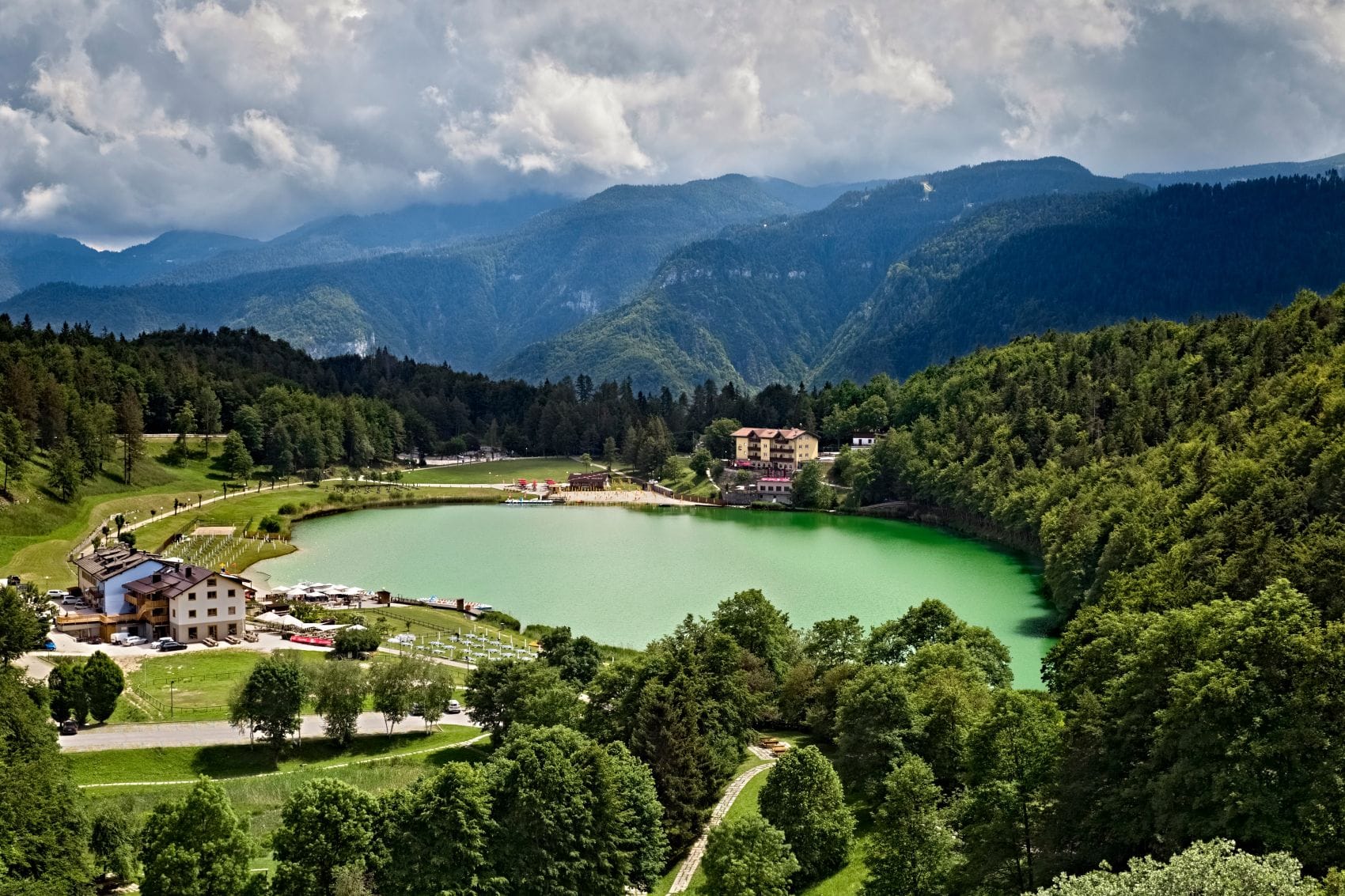 Blick auf den Lago di Lavarone im Trentino, umgeben von Wäldern und Bergen